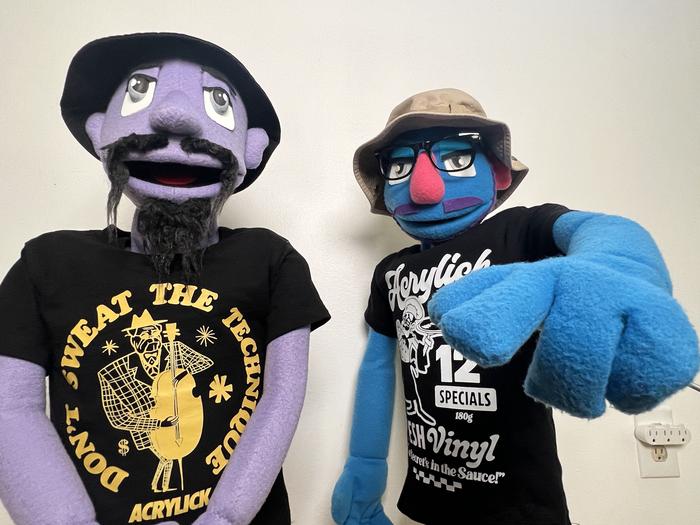 Two puppet characters posing together in band tees