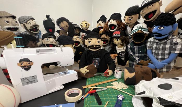 The puppet crew crowded around the sewing machine in the workshop