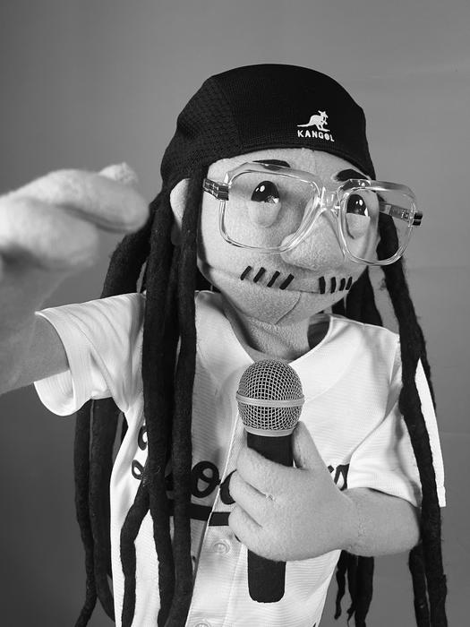 Puppet character with dreadlocks holding a microphone, black and white