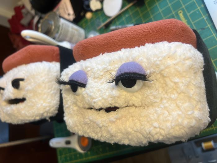 Two puppet heads in progress with eyelash detail
