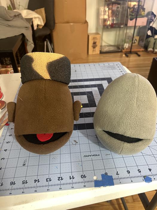Two puppet heads in progress side by side on the workbench