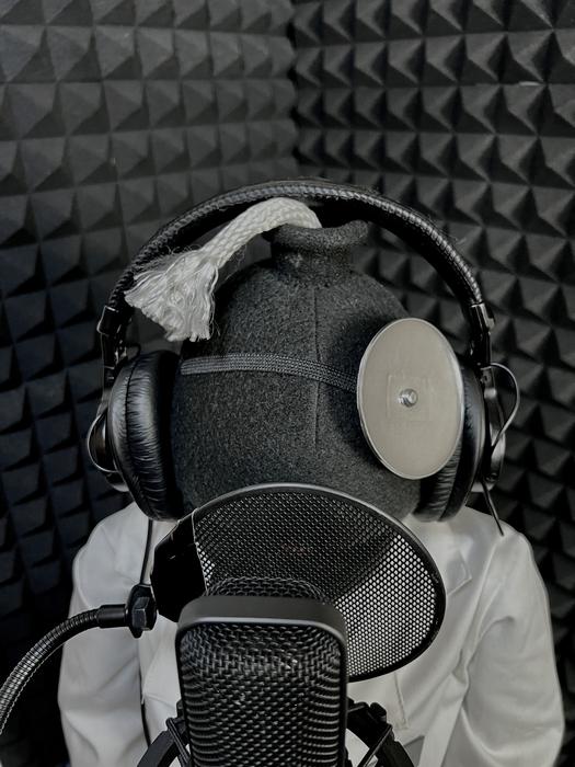 Puppet head wearing studio headphones in front of a microphone