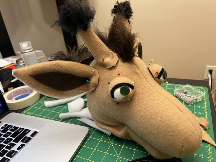 Tan puppet head in progress with big ears and one eye attached
